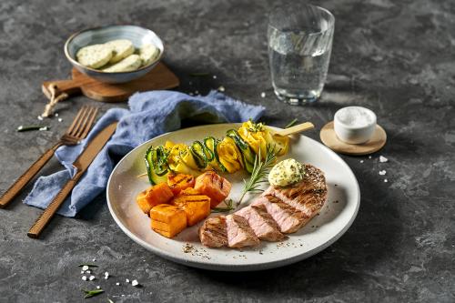 Veal rump steak in rosemary butter with roasted sweet potato cubes and accordion courgettes