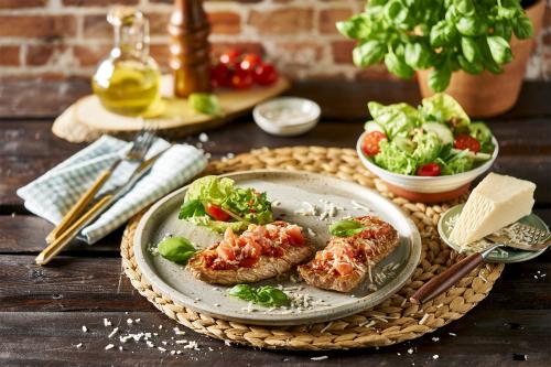 Kalfsschnitzel met kazige pizzatopping en bijpassende salade