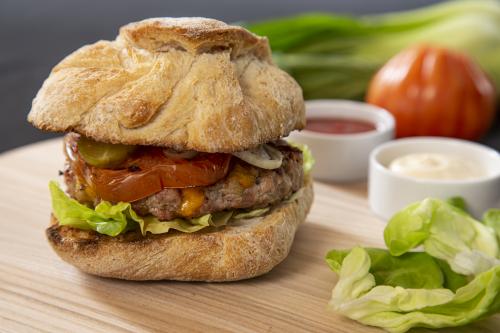 Sulla griglia: Burger di vitello con cheddar, insalata, pomodoro, cetriolo sottaceto e cipolla